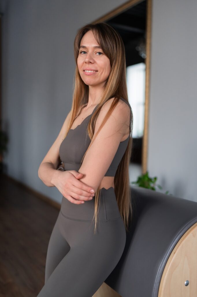 Pilates fitness trainer in pilates studio. Young sporty attractive woman wearing sportswear in yoga